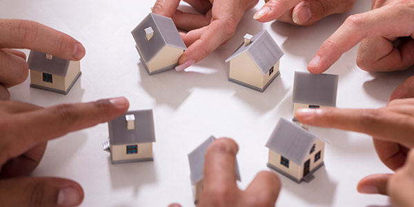 Hände und Häuser als Symbol für Eigentümergemeinschaft